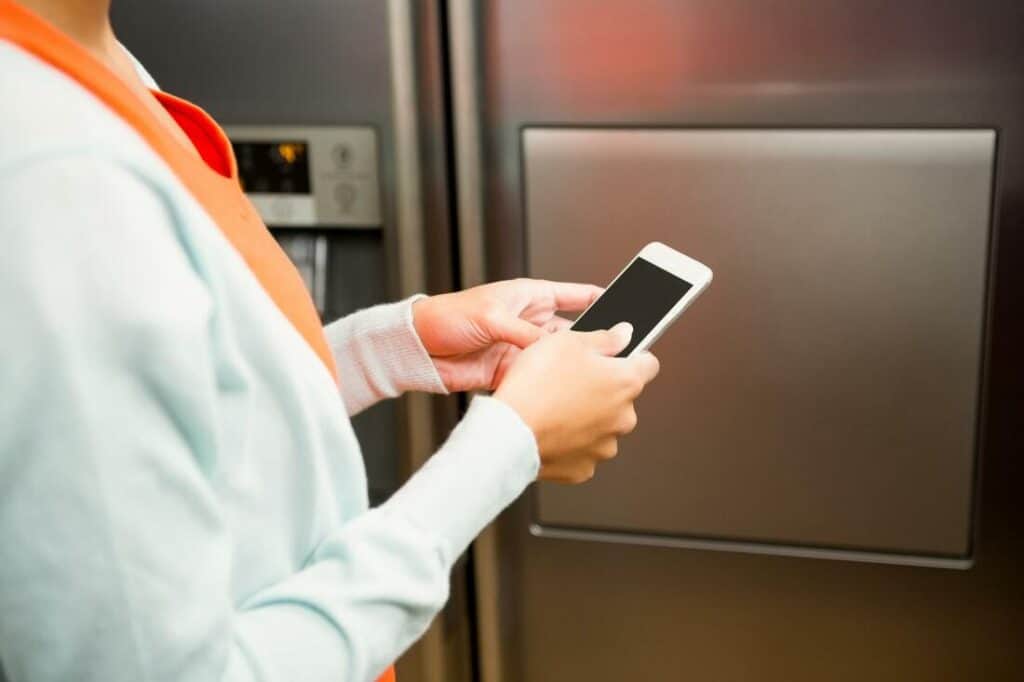 Woman Texting Refrigerator Appliance Repairman